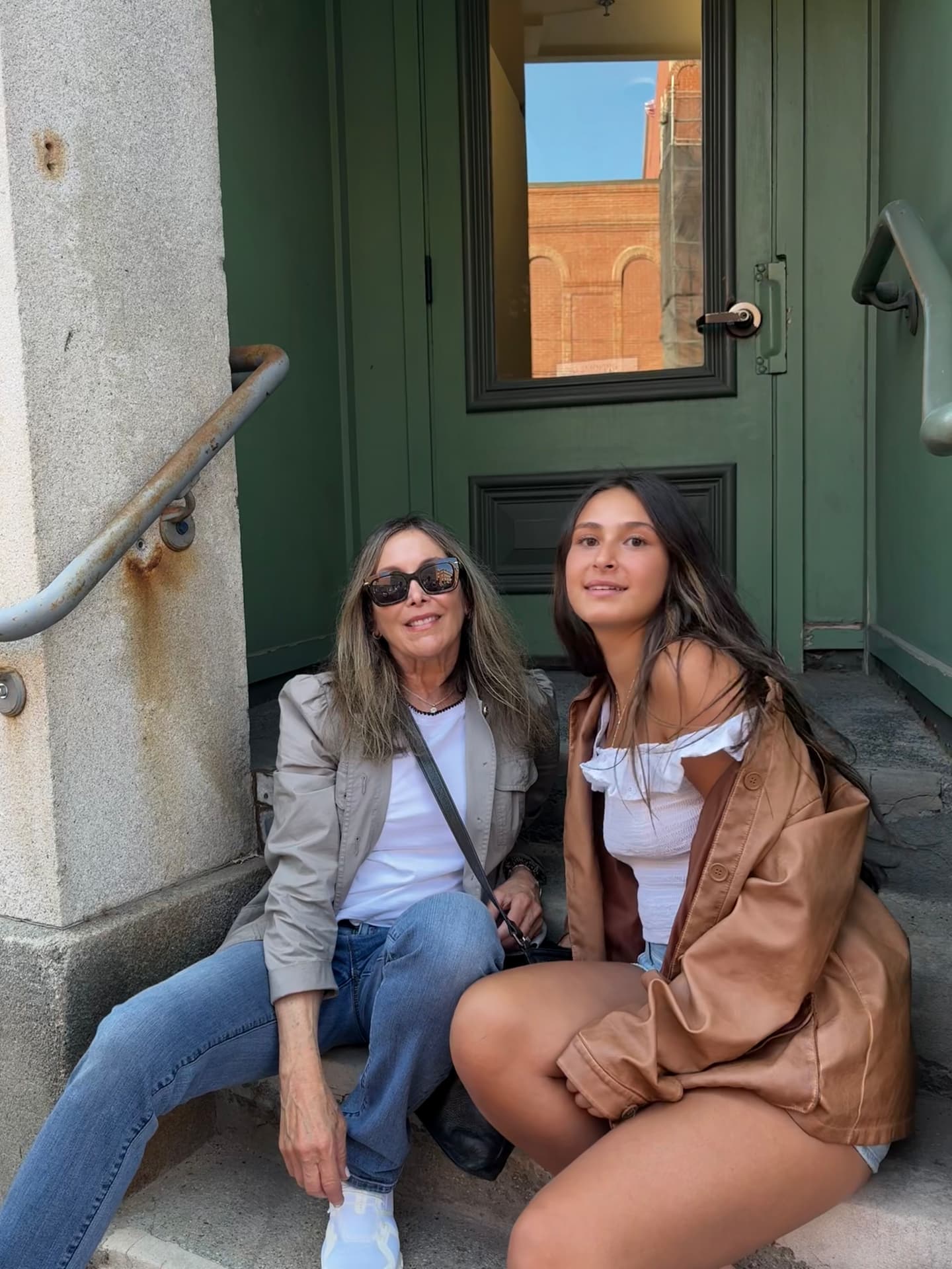Harrise sitting on a doorstep with a young woman